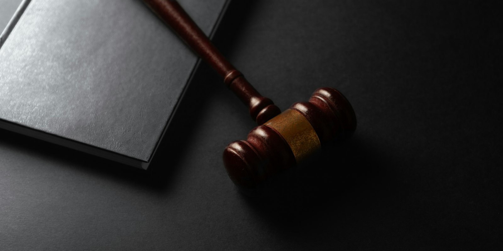¿Qué significa que tu sentencia esté en firme? Mazo de juez junto a un libro de leyes: qué significa que una sentencia esté en firme